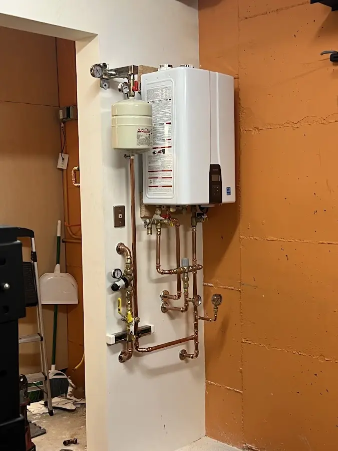 Plumbing technician inspecting water heater connections in Peters